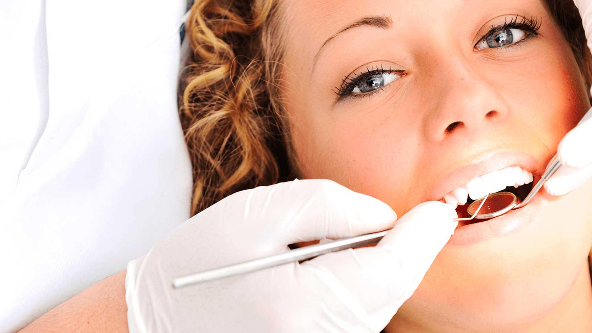 A close-up of a woman as a dentist examines her teeth