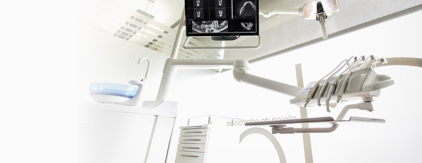 An overhead screen in a treatment room shows dental x-rays.