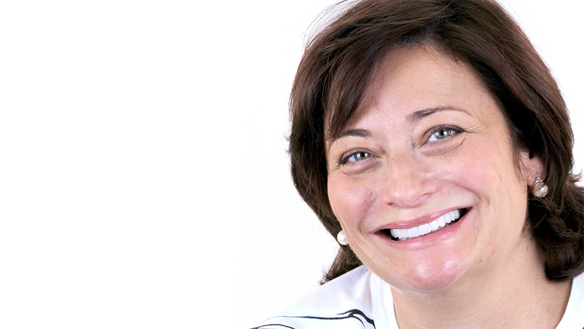 A woman smiles at the camera to show her natural-looking smile with veneers